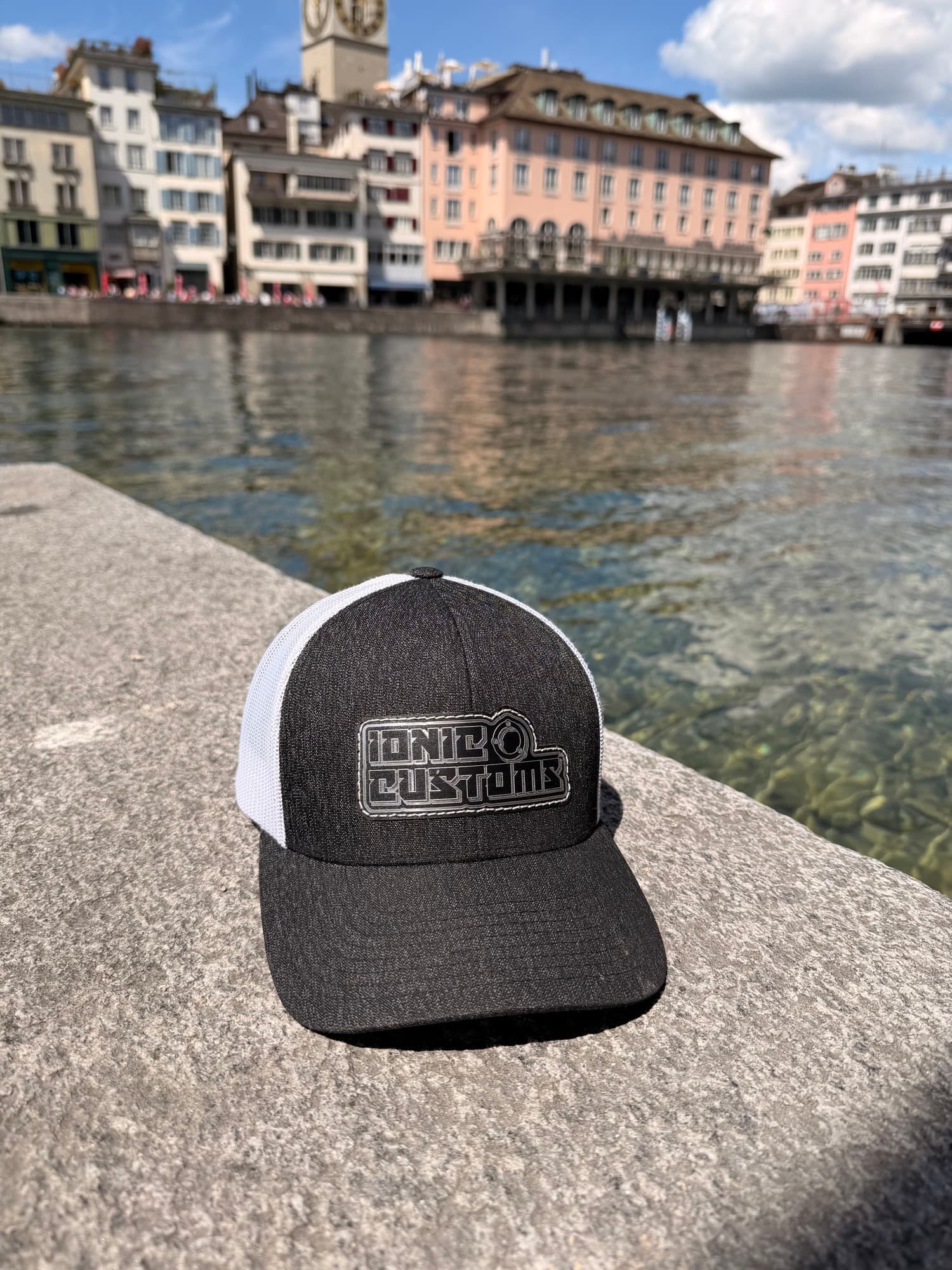 Charcoal and white trucker hat with engraved patch by the river