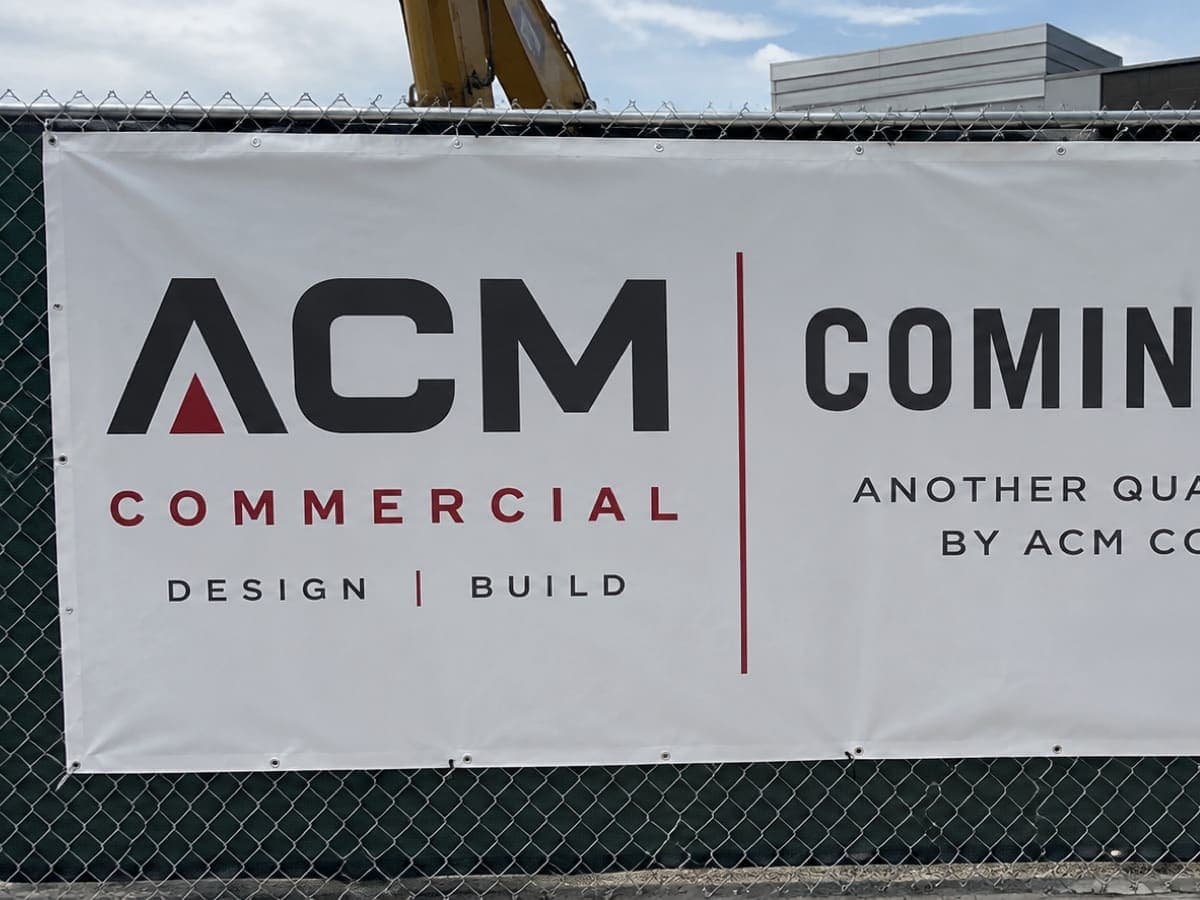 Grommeted vinyl banner zip-tied to a job-site fence